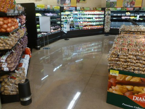 Produce displays sit on a polished cement floor at a grocery store.